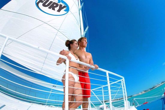 Two people on a boat with 'Fury' branding against a clear blue sky.